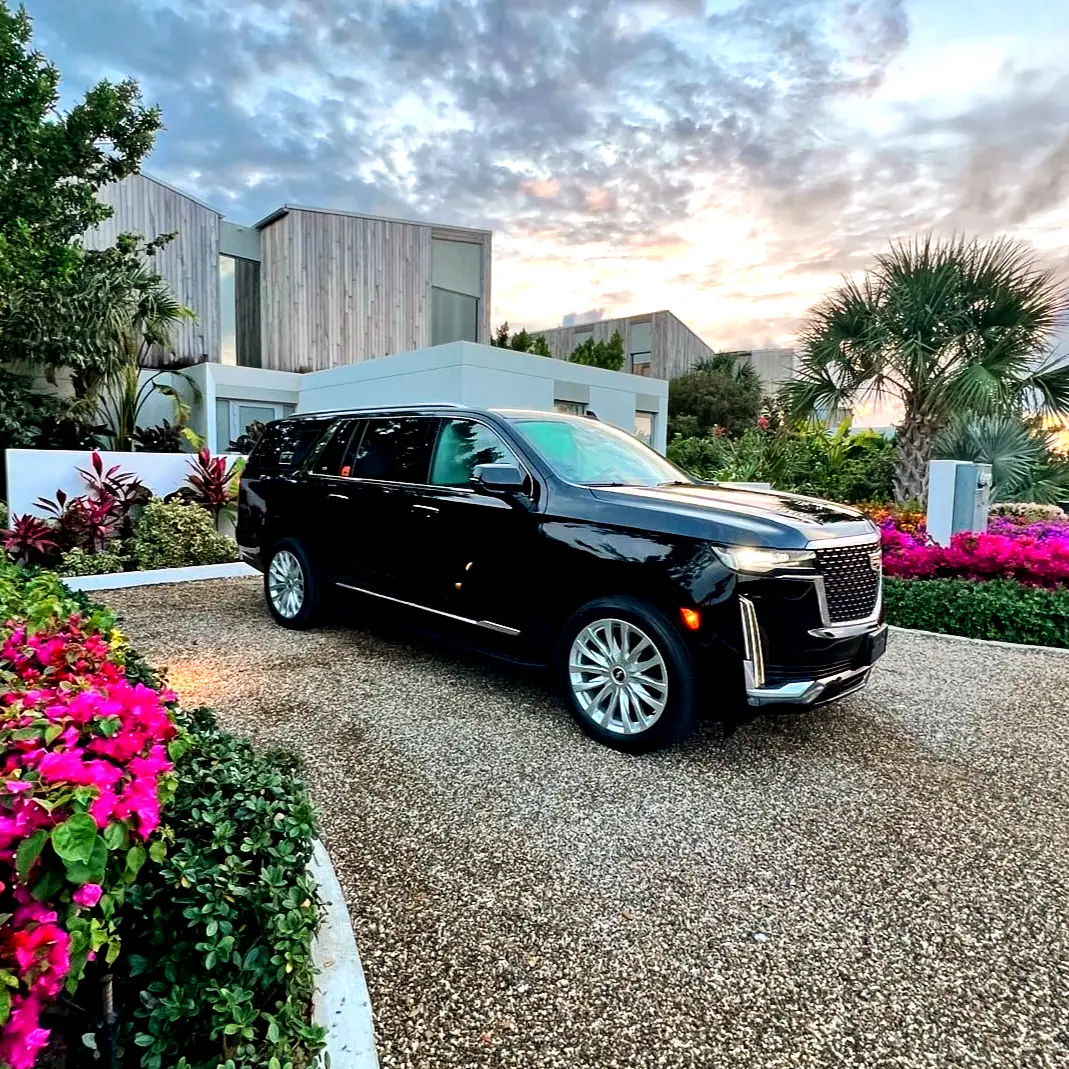 Black Cadillac Escalade parked on a gravel drive outside a villa in Providenciales